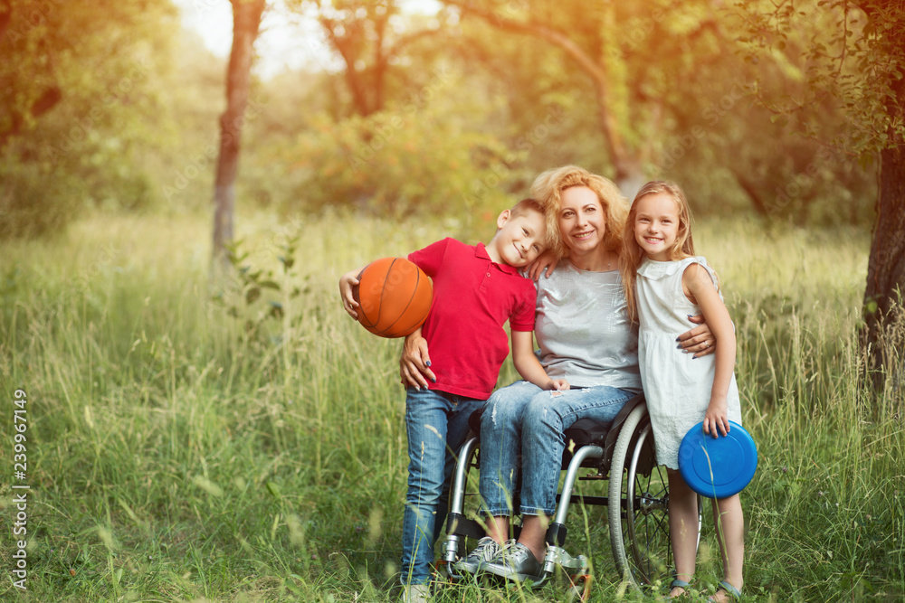 Family portrait. Woman in a wheelchair with her family outdoors. Family portrait. Woman in a wheelchair with her family outdoors.