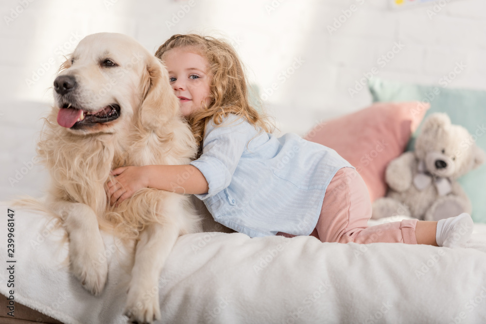 adorable kid hugging golden retriever on bed in children room adorable kid hugging golden retriever on bed in children room