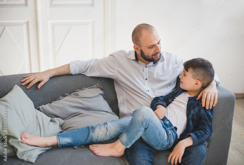 Daddy with son relaxing on sofa.