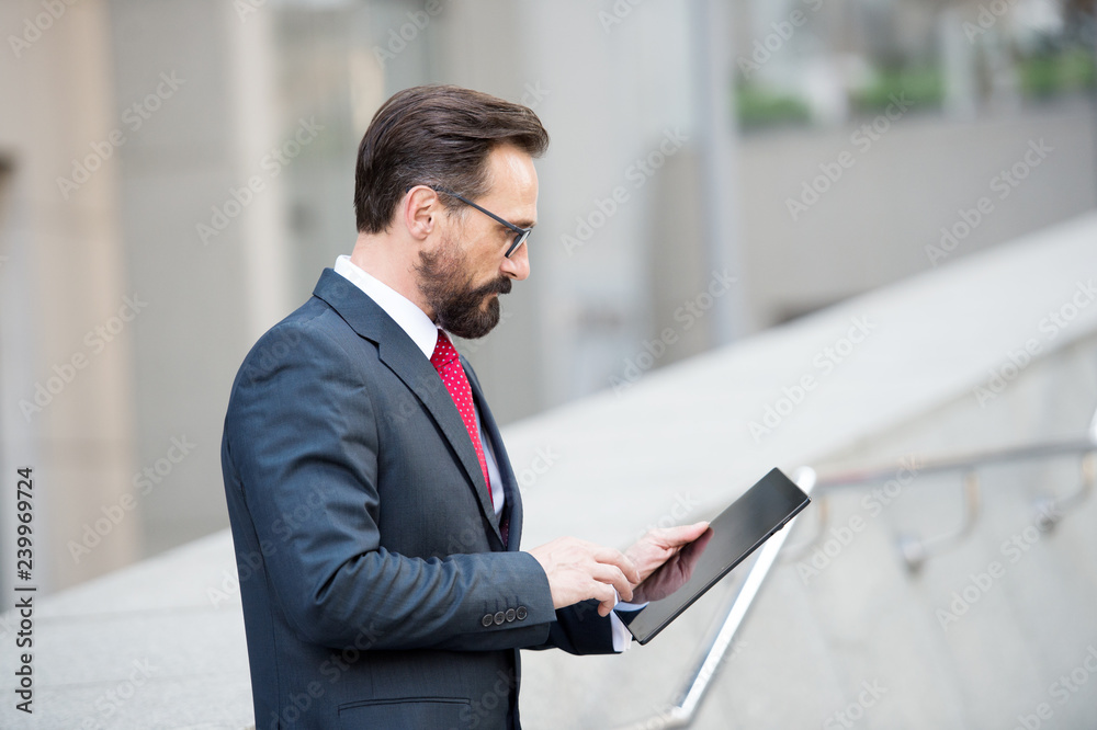 Fototapeta premium Profile of concentrated mature manager using a tablet in the street