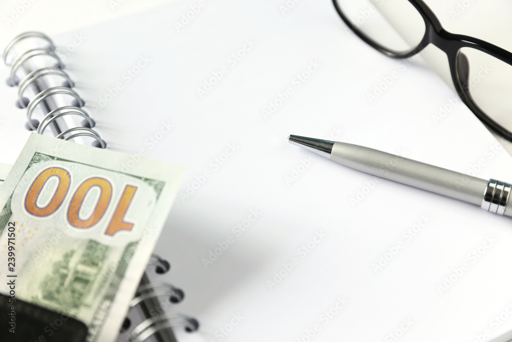 White blank notebook with silver pen and glasses and wallet with money White blank notebook with silver pen and glasses and wallet with money