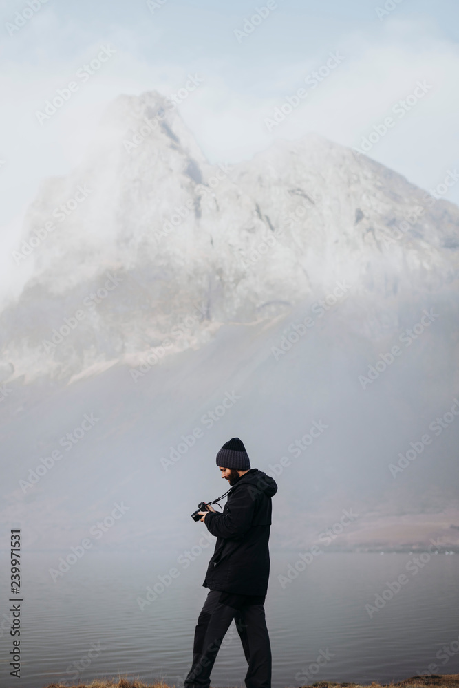 Anonymous tourist with camera against mountain in Iceland