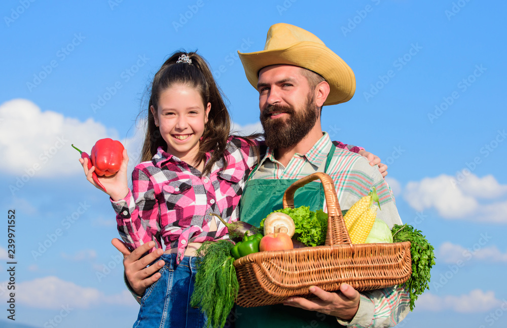 Family farm concept. Only organic and fresh harvest. Man bearded rustic farmer with kid. Farmer family homegrown harvest. Father and daughter hold basket harvest vegetables. Gardening and harvesting