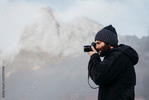 Anonymous tourist with camera against mountain in Iceland