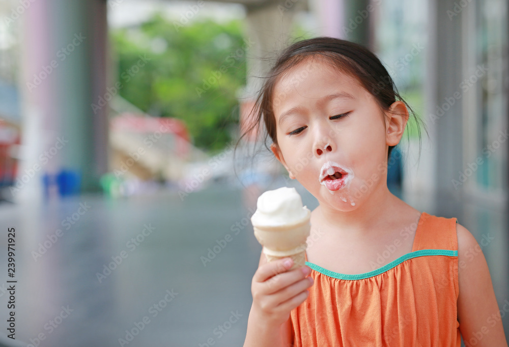 little Asian child girl enjoy eating ice cream cone. little Asian child girl enjoy eating ice cream cone.
