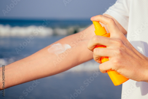 Fotografie closeup of a young caucasian man wearing a white T-shirt applying sunscreen to h