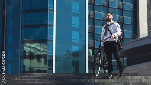 Handsome businessman carrying his bicycle while going on stairs