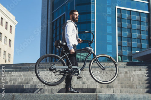 Businessman holding his bicycle while going on stairs