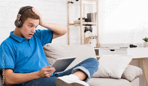Shocked teen guy reading news on tablet