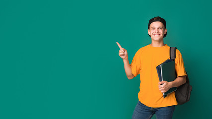 Teen student with books pointing on copy space