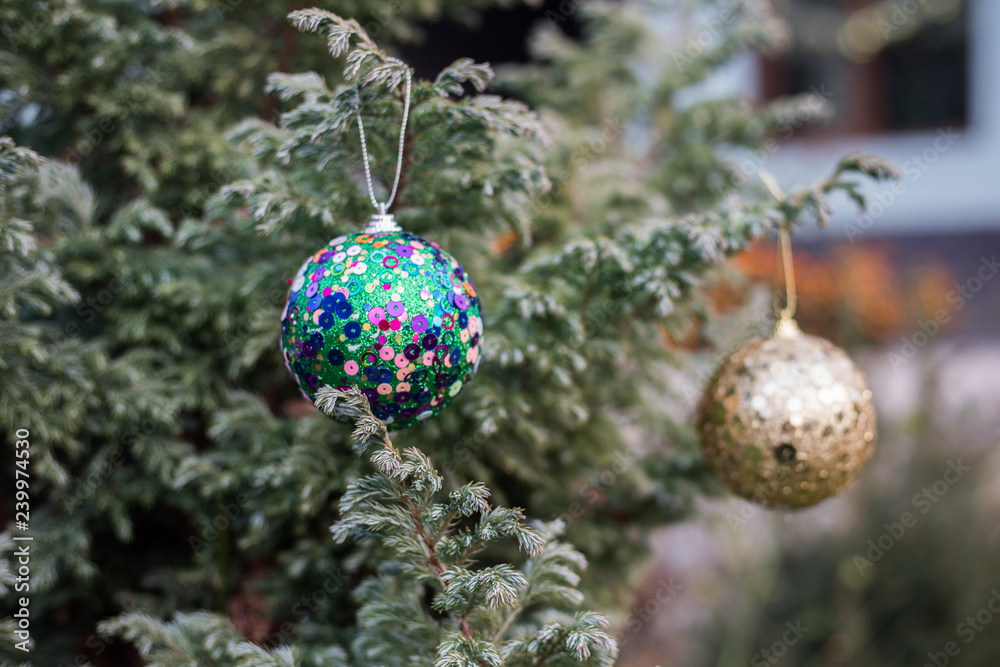 Obraz premium Christmas and New Year decoration on the pine tree branch with lights at the background at night outdoors. Concept of winter holidays.