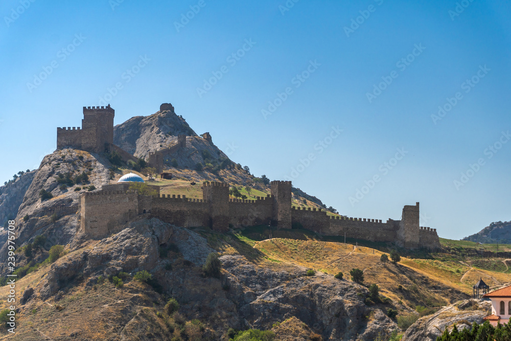 View of the Genoese fortress in the city of Sudak, Crimea, against a blue sky.