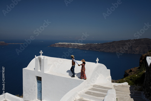Young couple looks down on the landscape of the island of Santorini