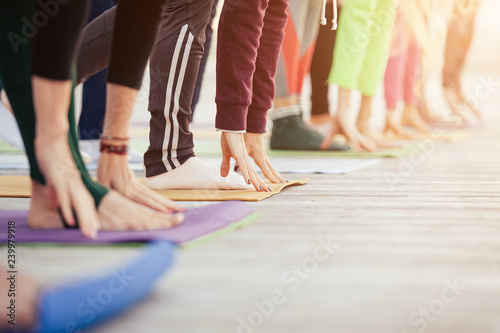 Yoga group concept. Sporty young people doing morning yoga class with yogi instructor. Students practicing uttanasana exercise, head to knees, working out. Stretching and flexibility training