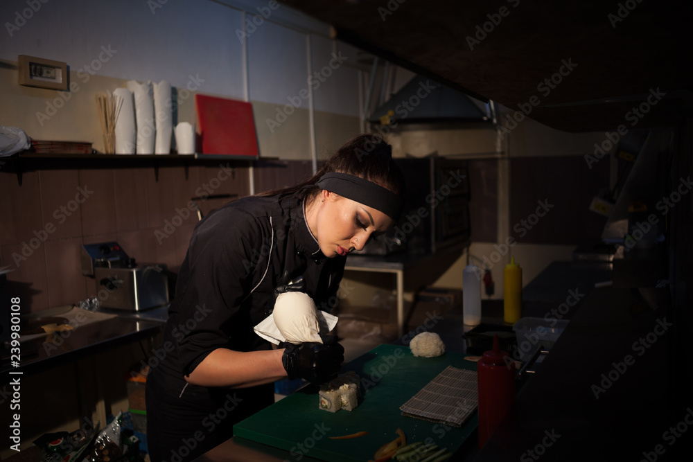 woman prepares delicious sushi in the kitchen at restaurant