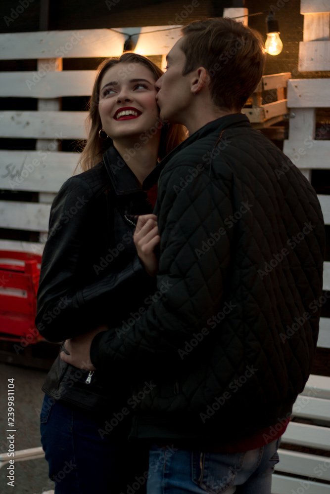couple in love, the guy kisses the girl on the cheek, evening, against the backdrop of a lantern, flowers.date couple in love, the guy kisses the girl on the cheek, evening, against the backdrop of a lantern, flowers.date