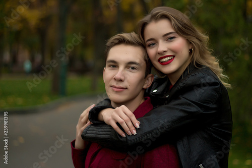 smiling girl hugging a guy from behind the neck, couple in love, date, love story