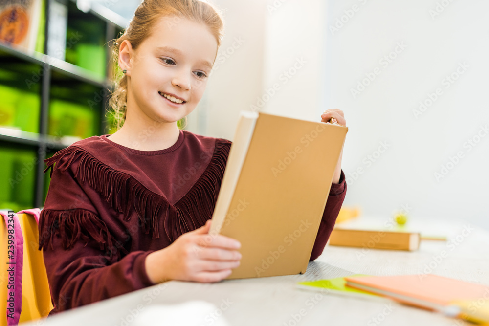 cute happy schoolgirl sitting and reading book in library cute happy schoolgirl sitting and reading book in library