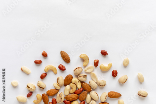 Assorted roasted and raw nuts scattered on white