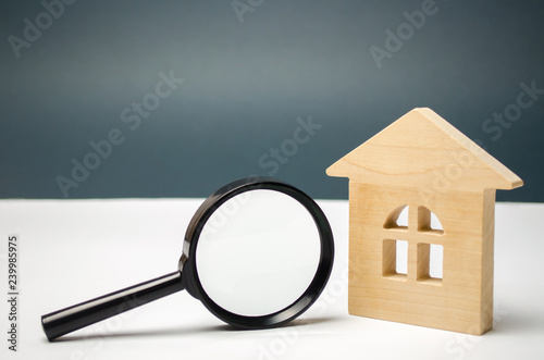 Wooden house and magnifying glass. Property valuation. Choice of location for the construction. House searching concept. Search for housing and apartments. Real estate concept. Home appraisal photo