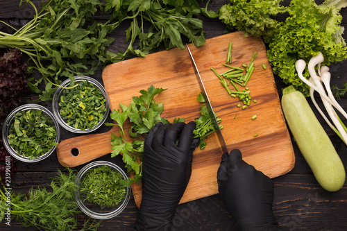 Hands in black disposable gloves cutting parsley photo