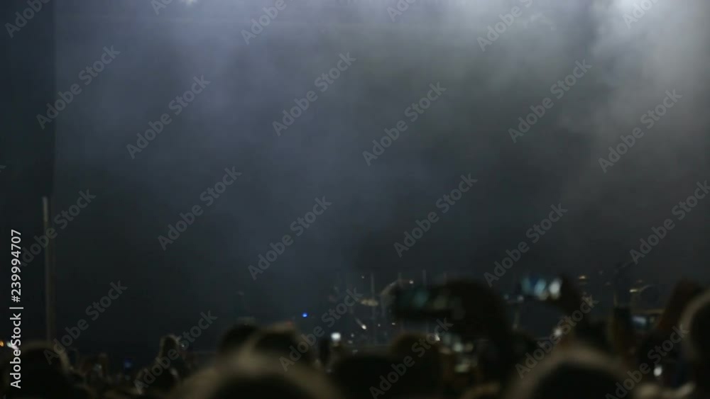 Spectators filmed the artist on the phone during a performance on stage. Spectators at the concert photographed artist. Fan taking photo of concert at festival.