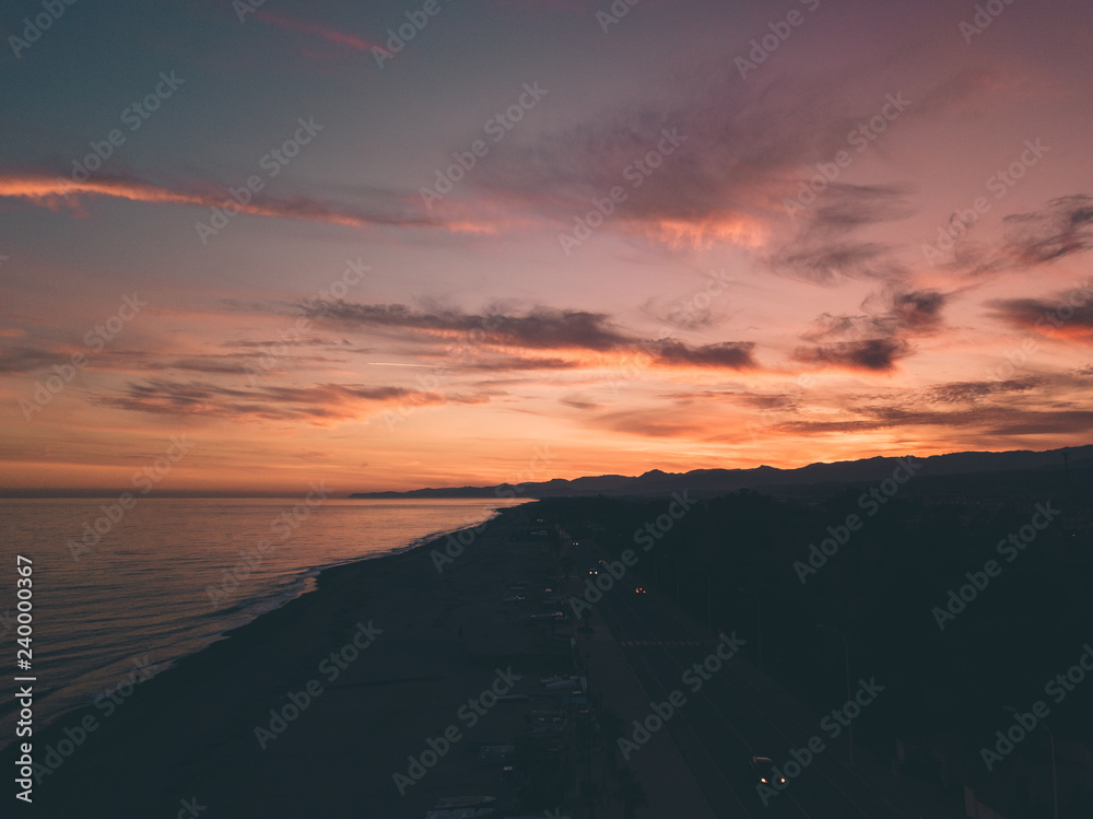 Bellissimo cielo al tramonto infuocato con nuvole arancione e rosso in riva all'oceano calmo. Vista aerea