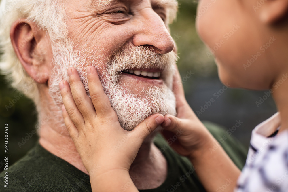 Old smiling man and his granddaughter looking each other - obrazy, fototapety, plakaty 