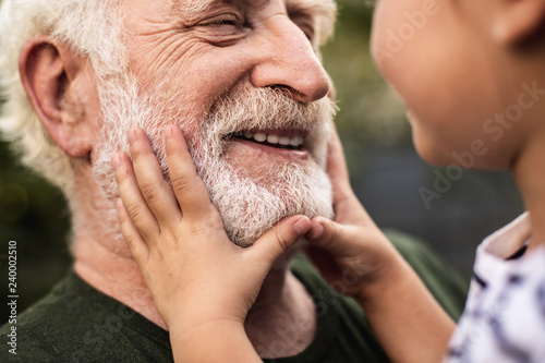 Old smiling man and his granddaughter looking each other photo