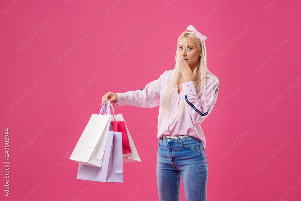 Happiness, consumerism, sale and people concept - smiling young blond woman with shopping bags over pink background Happiness, consumerism, sale and people concept - smiling young blond woman with shopping bags over pink background