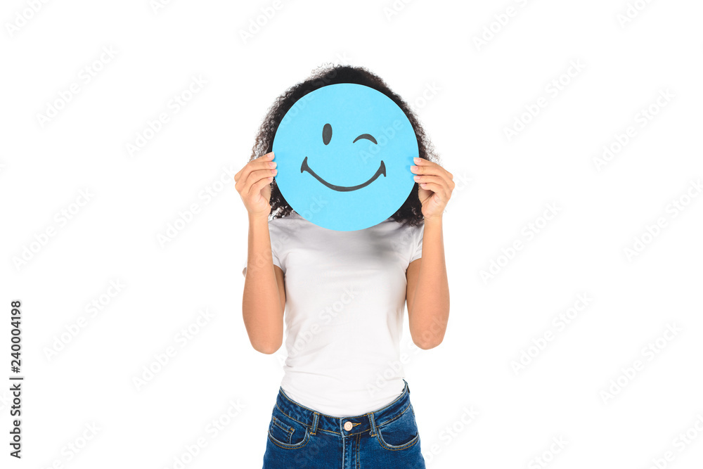 african american girl holding round, blue sign with winking face expression isolated on white african american girl holding round, blue sign with winking face expression isolated on white