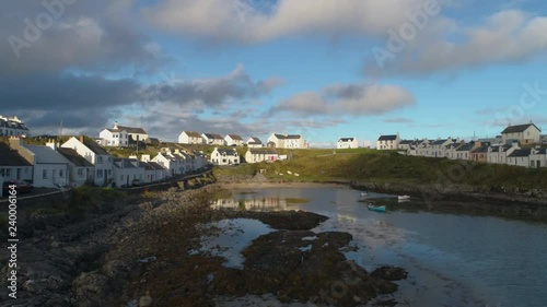 Cinematic Aerial Drone Shot in Scottish Highlands, moving slowly low over sea towards Portnahaven bay on the Isle of Islay photo