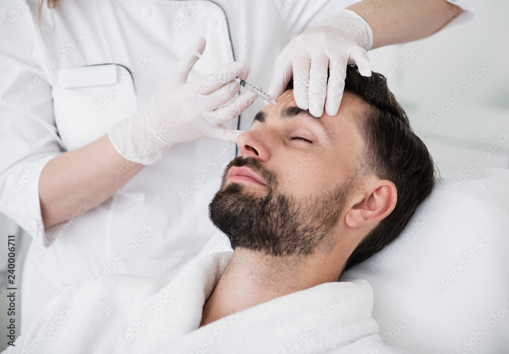 Calm man closing his eyes during the beauty injection procedure Calm man closing his eyes during the beauty injection procedure