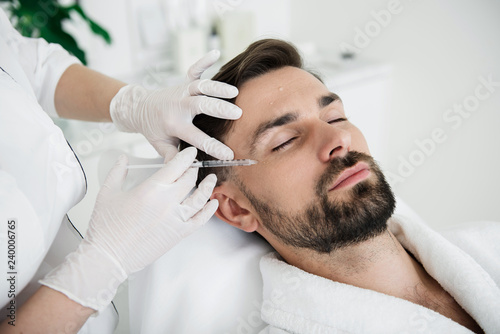 Man closing his eyes while getting beauty injection