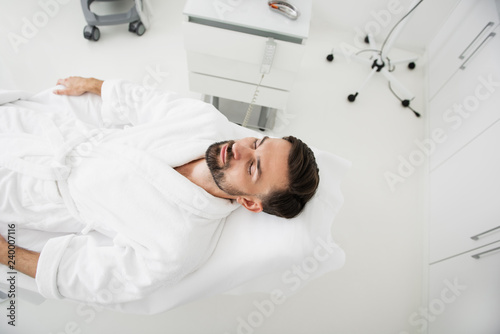 Top view of calm man relaxing in spa salon and smiling