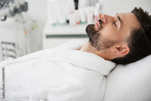 Peaceful man closing his eyes in spa salon