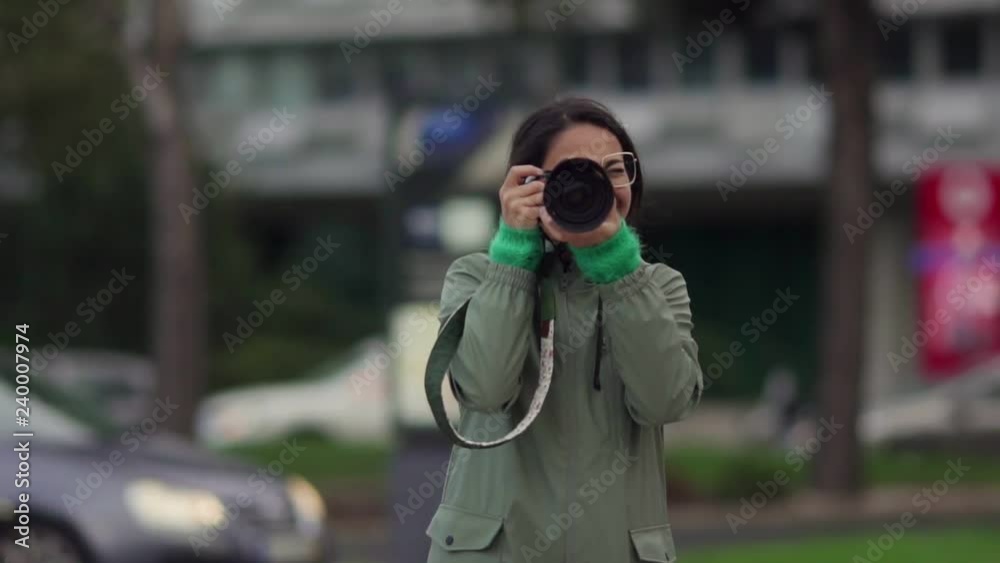 Young Asian girl taking picture turning into camera. Single traveler smiling and shooting with professional camera, turning directly into camera. Photography concept. Young Asian girl taking picture turning into camera. Single traveler smiling and shooting with professional camera, turning directly into camera. Photography concept.