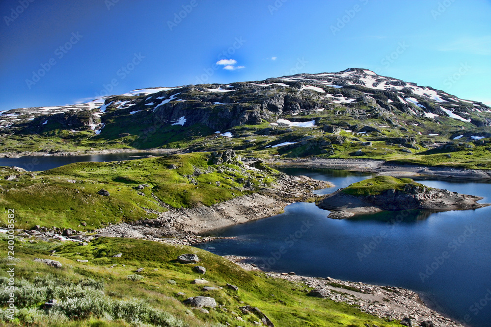 The beautiful alpine lake in Scandinavia with remnants of snow nearby