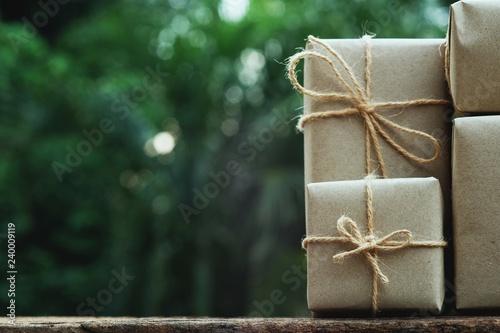 Stack of simple eco friendly gift box package wrap with brown paper in old wooden table background, green present concept