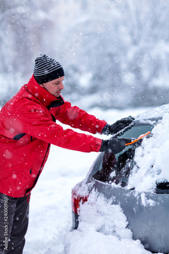 man removing snow from car. Man cleaning snow from car windshield with brush, close up. Snowy winter weather. Car in snow after snowstorm. .