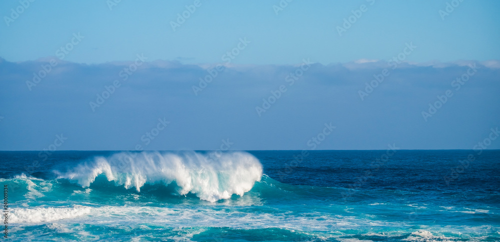 Single perfect wave in blue deep dangerous ocean - perfect barrel for brave surfers - coast in background for touristic scenic place - enjoy the beauty of the world and the feeling of the sea