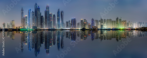 Die beleuchtete Skyline der Dubai Marina bei Nacht mit Reflektionen in der Bucht