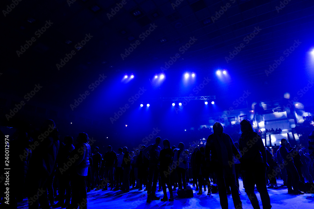 Concert crowd in the rays of blue spotlights.