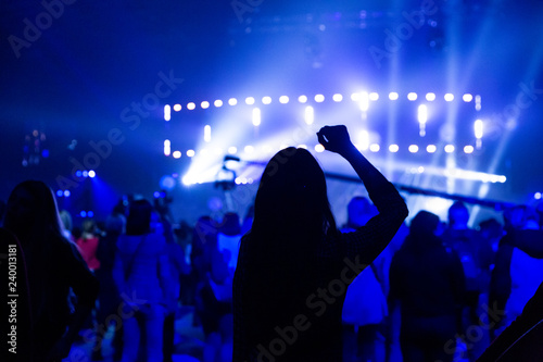Silhouette of a dancing girl at a concert among a crowd of spectators.