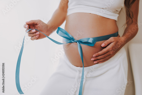 Tender mum with ribbon on stomach waiting a baby