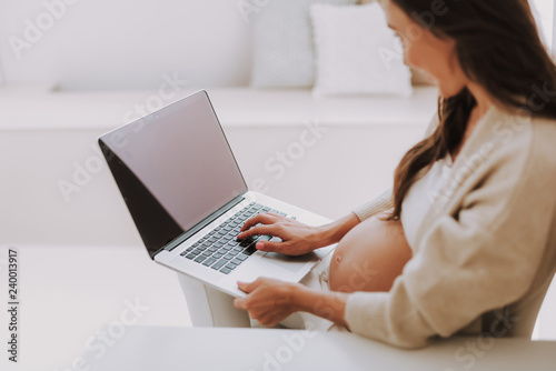 Tender young woman using pc laptop and typing text on keyboard