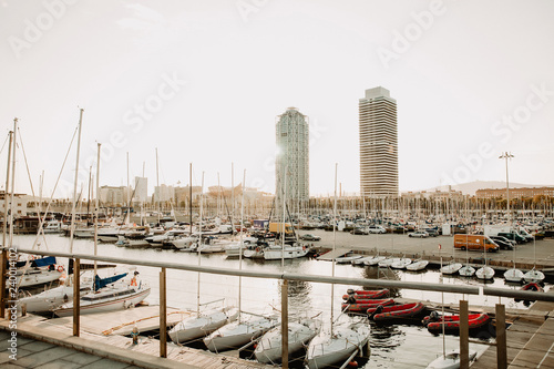 Sunny photo overlooking the yachts, boats and the modern city of Spain Barcelona during sunset