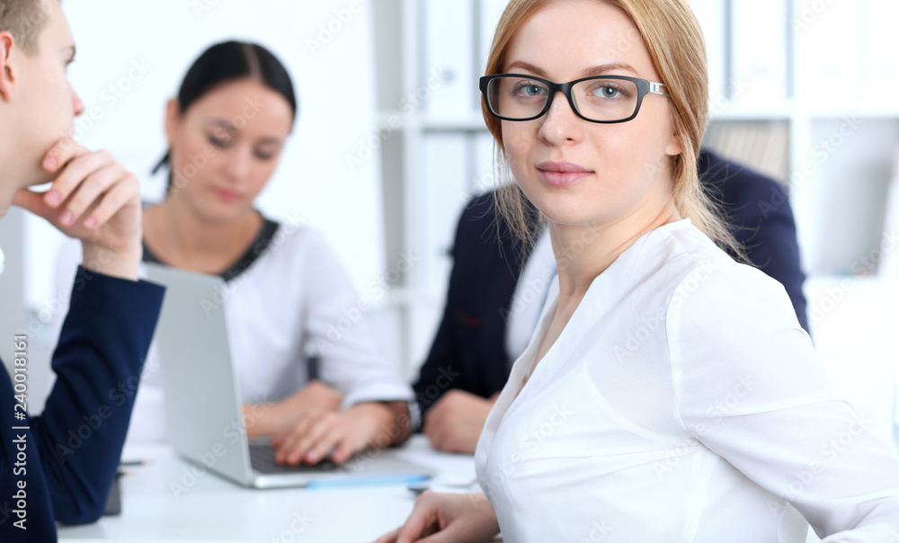 Business People group at meeting in office. Focus at beautiful cheerful smiling businesswoman. Conference, corporate training or brainstorming of team. Success and negotiation concept Business People group at meeting in office. Focus at beautiful cheerful smiling businesswoman. Conference, corporate training or brainstorming of team. Success and negotiation concept