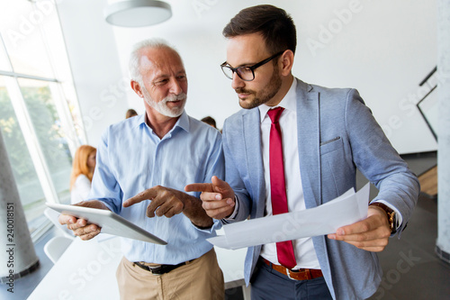 Mature boss and young business man working together in office