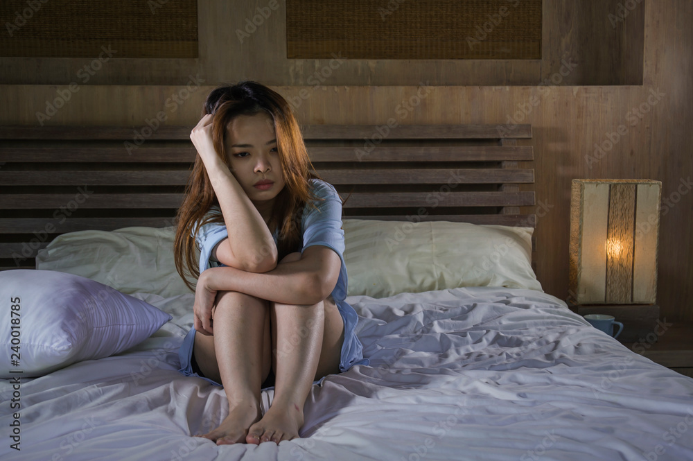 young depressed Asian Korean woman crying on bed at night having depression problem and anxiety crisis feeling sad in girl suffering broken heart or cyber bullying